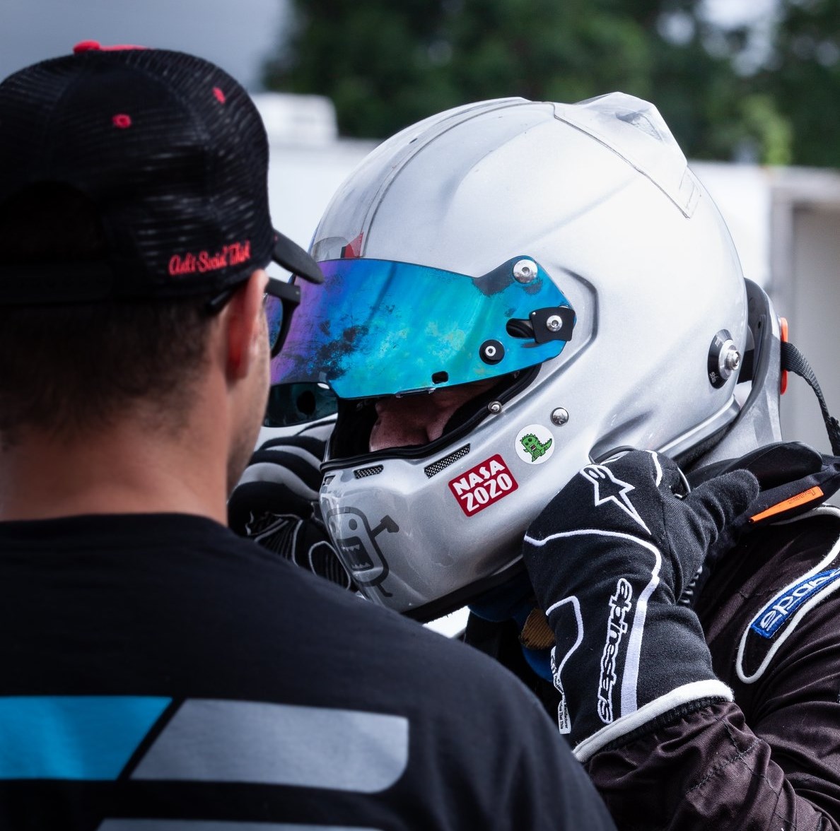 A helmeted driver getting ready with a Check6ix crew member at the track