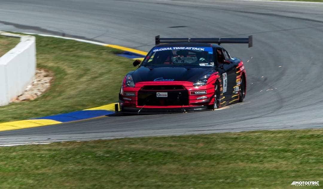 A red and black Nissan GT-R from the Check6ix archive attacking a corner at Road Atlanta